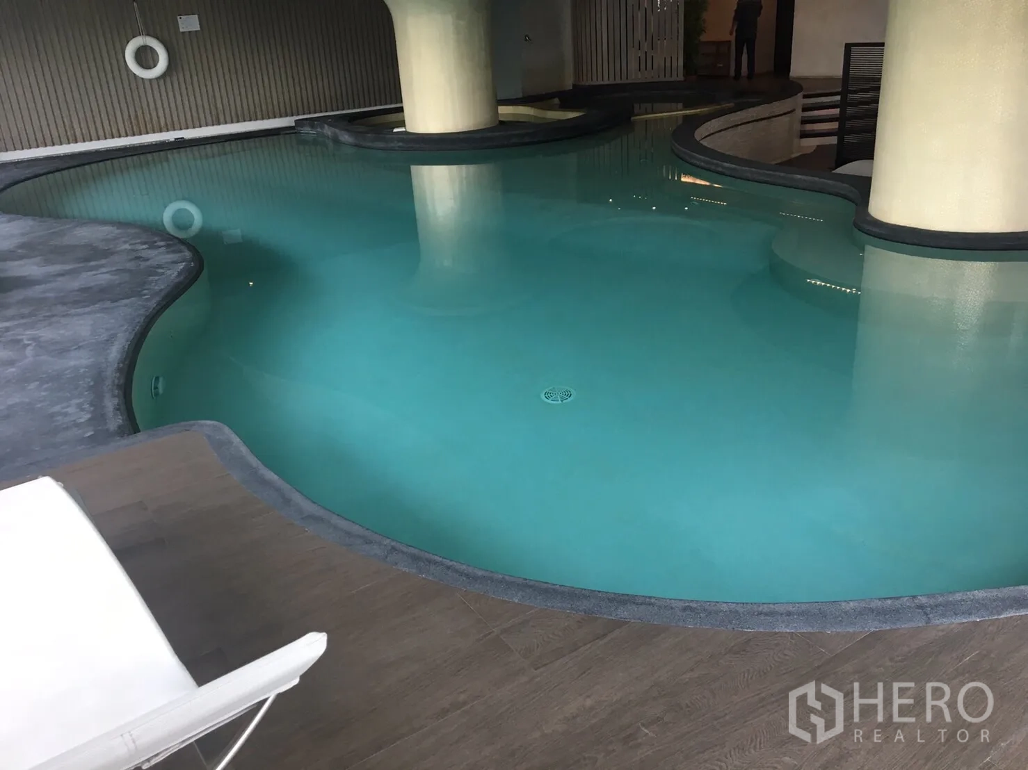 Condominium for rent in Phaya Thai, Bangkok - Curved indoor swimming pool with deck seating and ambient lighting.