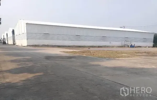 货栈 出租在Pathum Thani - 金属板外墙的仓库外观，前方宽阔混凝土场地