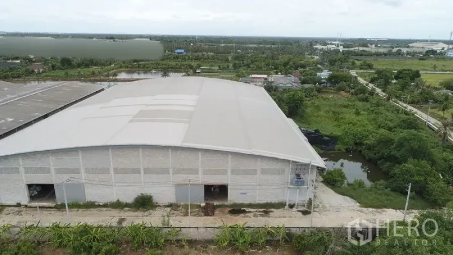 โรงงาน ให้เช่าหรือขายในKrathum Baen, Samut Sakhon - ภาพโดรนแสดงอาคารคลังสินค้าโครงหลังคาชิ้นเดียว ถนนทางเข้าและบ่อใกล้พื้นที่สีเขียว
