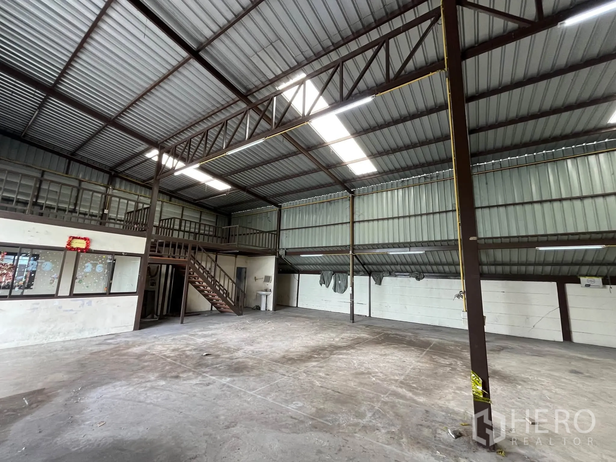 โกดัง for rent in Prawet, Bangkok - พื้นที่โกดังมองเห็นหน้าต่างสำนักงาน บันไดขึ้นชั้นลอย และเสาโครงเหล็ก.