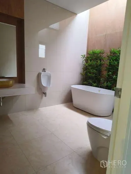 Detached House for rent in Phra Khanong, Bangkok - Bright bathroom with a freestanding bathtub, urinal, toilet and indoor greenery.