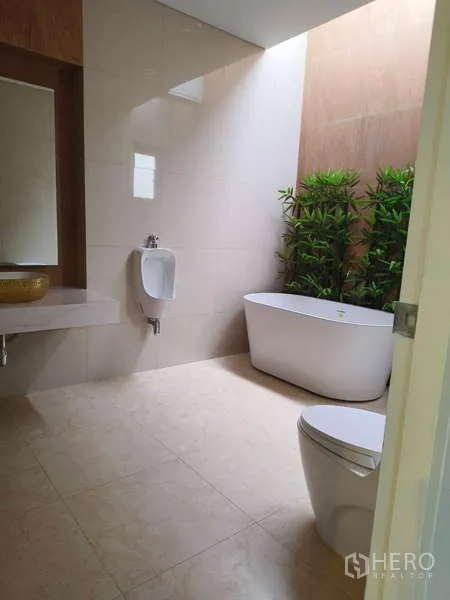 Detached House for rent in Phra Khanong, Bangkok - Bright bathroom with a freestanding bathtub, urinal, toilet and indoor greenery.