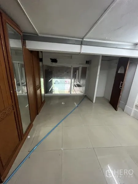 Shophouse for rent in Khlong Toei, Bangkok - Upper-floor open room with wardrobe cabinets, a sliding glass partition, and tiled floors.