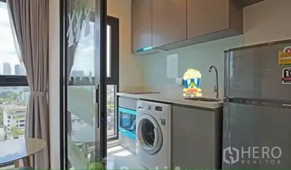 公寓 出租在Khlong Toei, Bangkok - 紧凑厨房带洗衣机与阳台门，可见曼谷城市景观