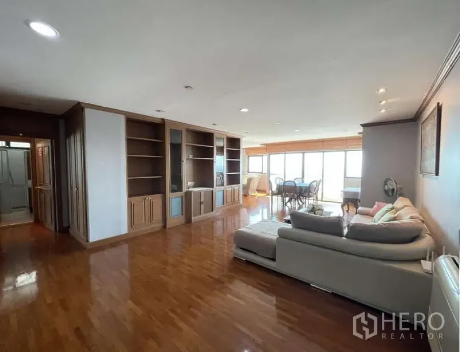 Condominium for rent - Wide living room with glossy wood floors, built-in shelving and dining area by windows.