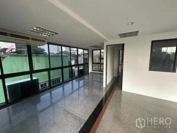 办公空间 出租在Sathon, Bangkok - 转角办公区，环幕窗户与亮面地坪，并设通往独立房间的门。
