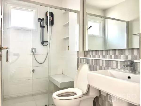 Detached House for rent in Prawet, Bangkok - Clean bathroom with glass-enclosed shower, handheld shower, bench seat and wide mirror.