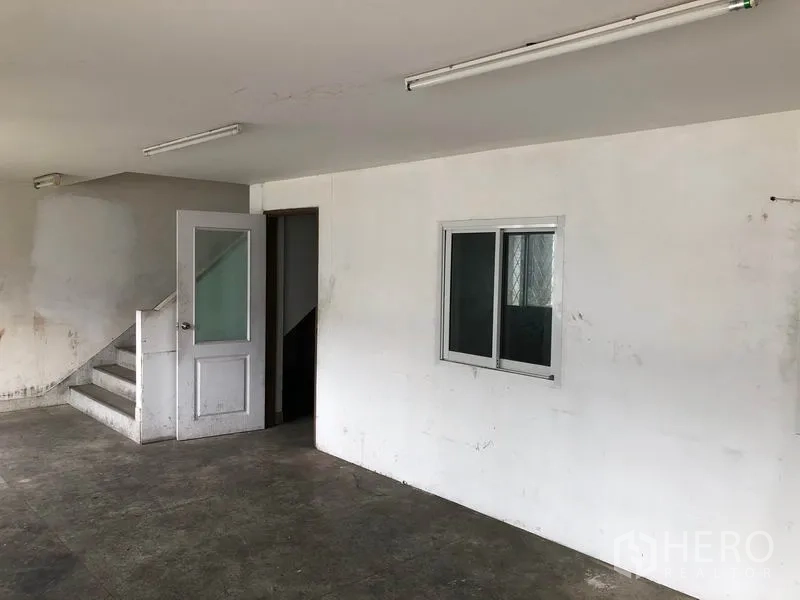 Factory for rent in Nonthaburi - Office area with a door and staircase leading to an upper level.