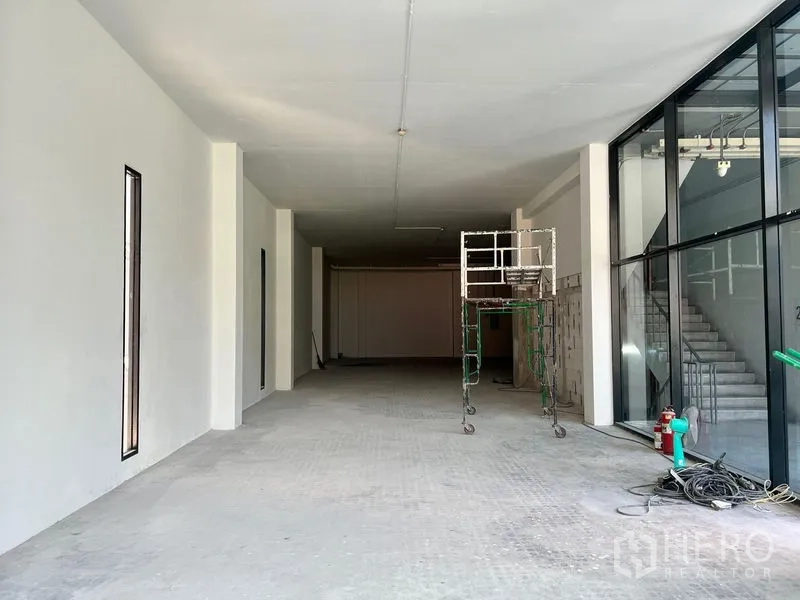 Retail Space for rent - Long retail unit with full glass frontage, high ceiling and scaffold near stairway and fire hydrant.