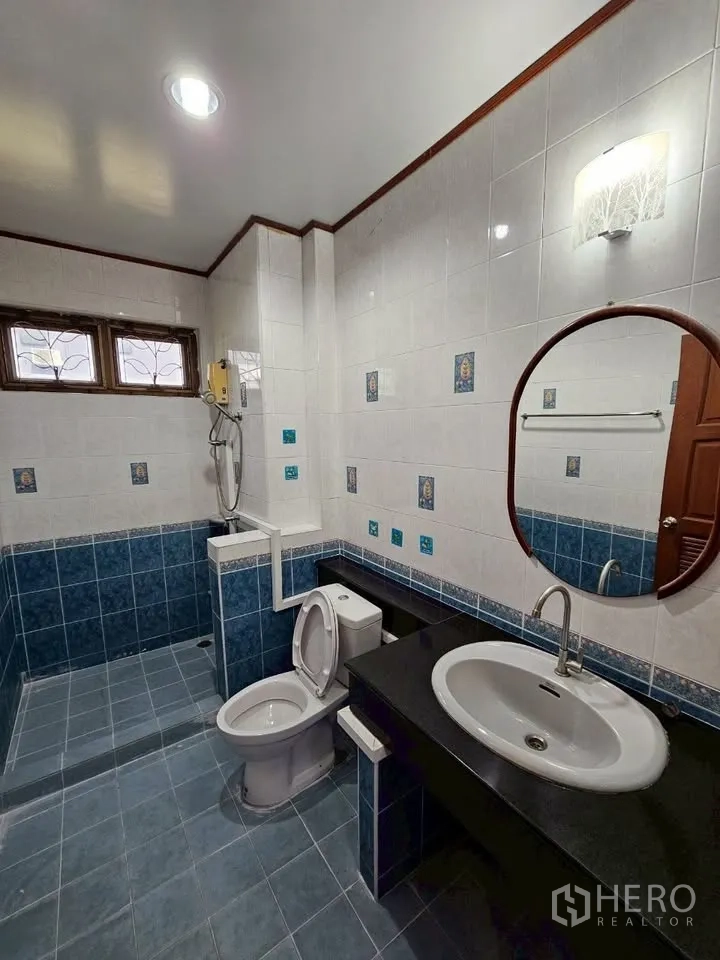 带办公室的家 for rent in Wang Thonglang, Bangkok - 蓝白色瓷砖浴室，步入式淋浴、坐便与长台面圆镜。