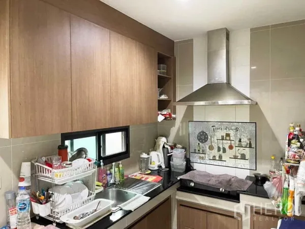 独立式住宅 出售在Prawet, Bangkok - 封闭式泰式厨房，木质柜体、水槽与不锈钢抽油烟机。