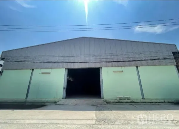 คลังสินค้า ให้เช่าในBang Phli, Samut Prakan - ด้านหน้าโกดังหลังคาเมทัลชีท ประตูกลางเปิดอยู่ ใต้ท้องฟ้าสดใส