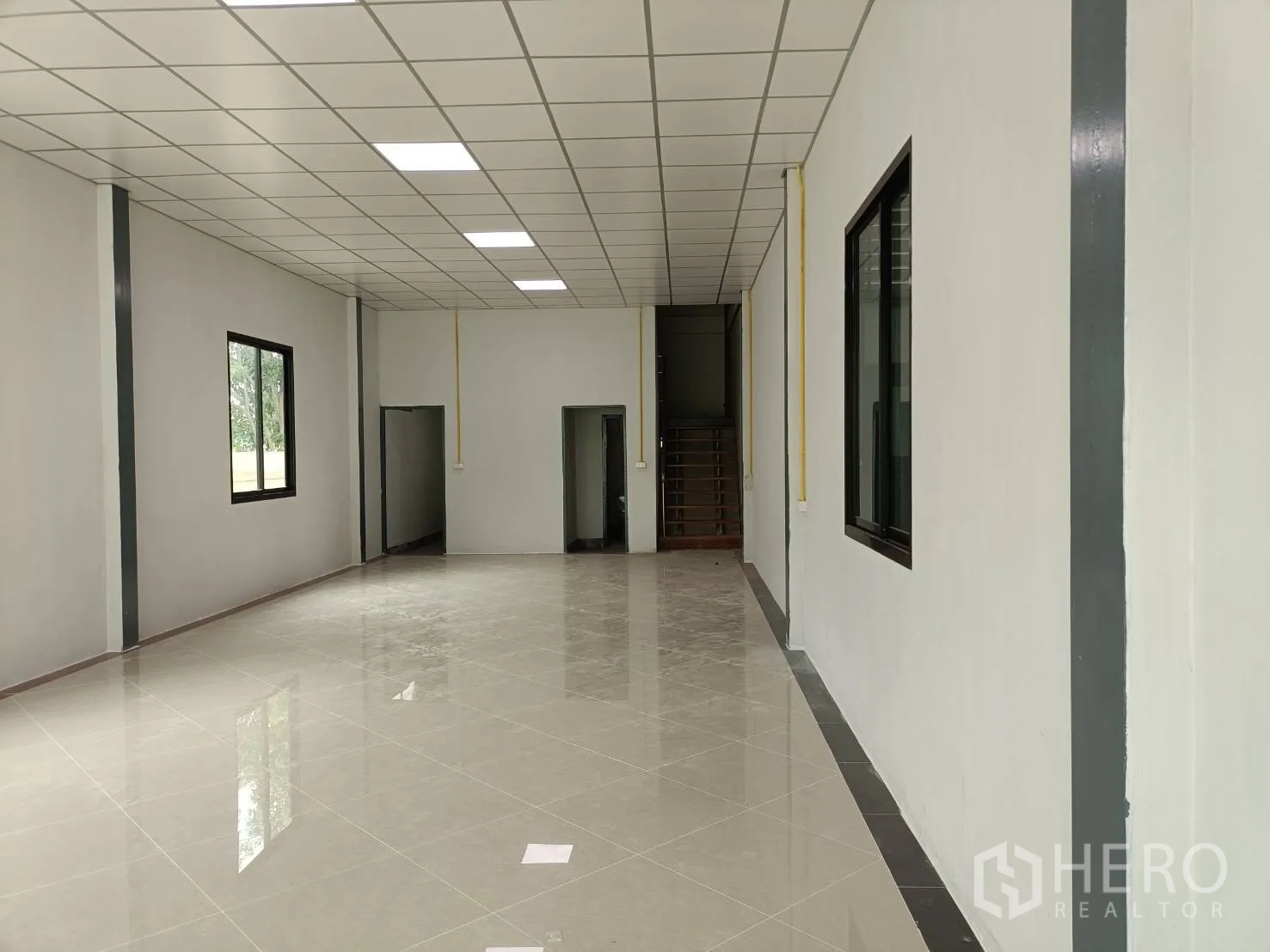 工厂 出租在Lam Luk Ka, Pathum Thani - 办公室大厅望向楼梯，吊顶灯与多扇侧窗。