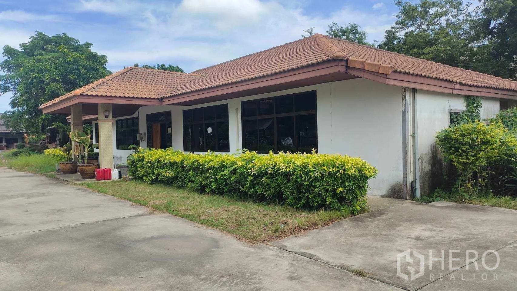 โรงงาน ขายในNikhom Phatthana, Rayong - มุมมองด้านข้างอาคารสำนักงานพร้อมแนวพุ่มไม้และทางเข้าคอนกรีต