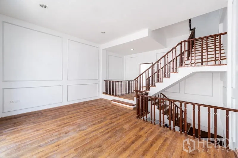 Townhouse for sale - Upper-floor family area with wood flooring and an L-shaped staircase.