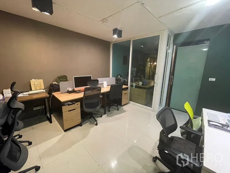 带办公室的家 出售 - 办公间内多张书桌与人体工学椅，旁有玻璃隔断。