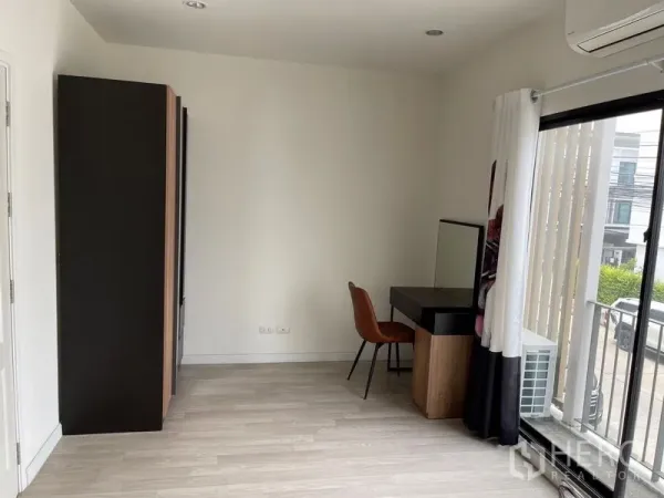 Townhouse for rent in Bang Kapi, Bangkok - Bright room with wardrobe, dressing desk, sliding glass door and light wood flooring.