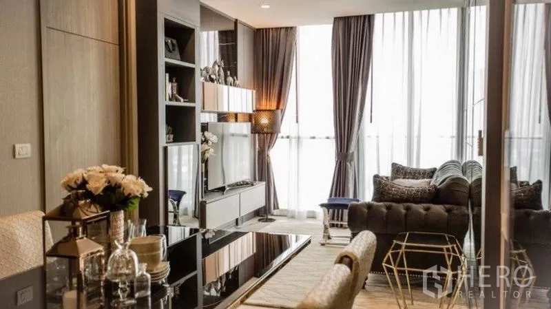 Condominium for rent in Pathum Wan, Bangkok - Elegant living and dining area with tufted sofa, TV wall, and floor-to-ceiling windows.