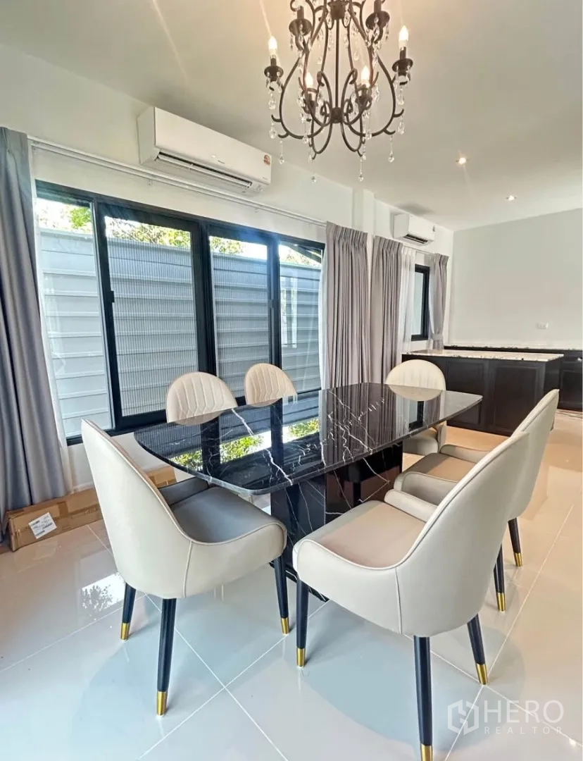 Semi-detached House for rent in Bang Phli, Samut Prakan - Dining room with black marble table, upholstered chairs and chandelier beside large windows.
