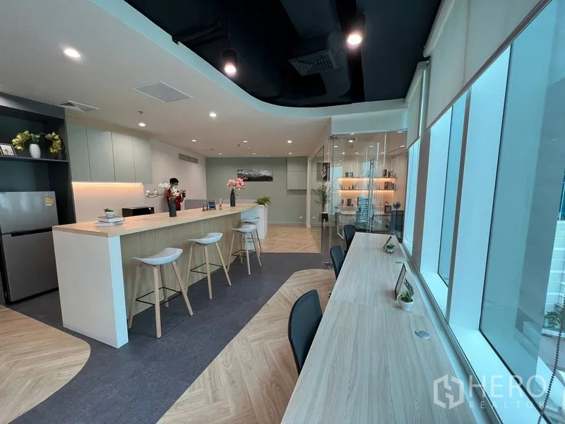Office Space for rent - Bright workspace with window-side desks, bar counter and glass office, city view.