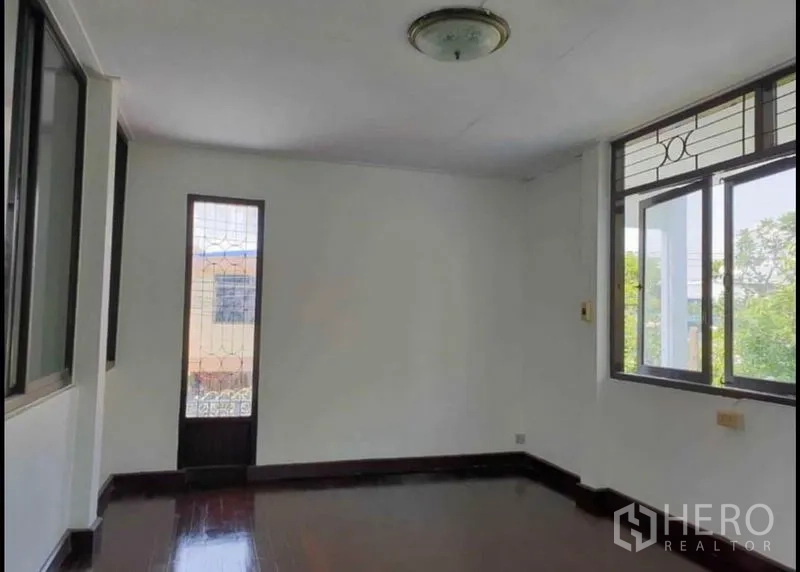独立式住宅 出租在Lat Phrao, Bangkok - 二层卧室，木地板、采光窗与通往阳台的窄玻璃门。