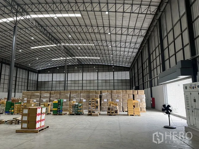 Warehouse for rent in Lat Krabang, Bangkok - High-clear warehouse interior with steel truss roof, bright lighting and pallets of goods.