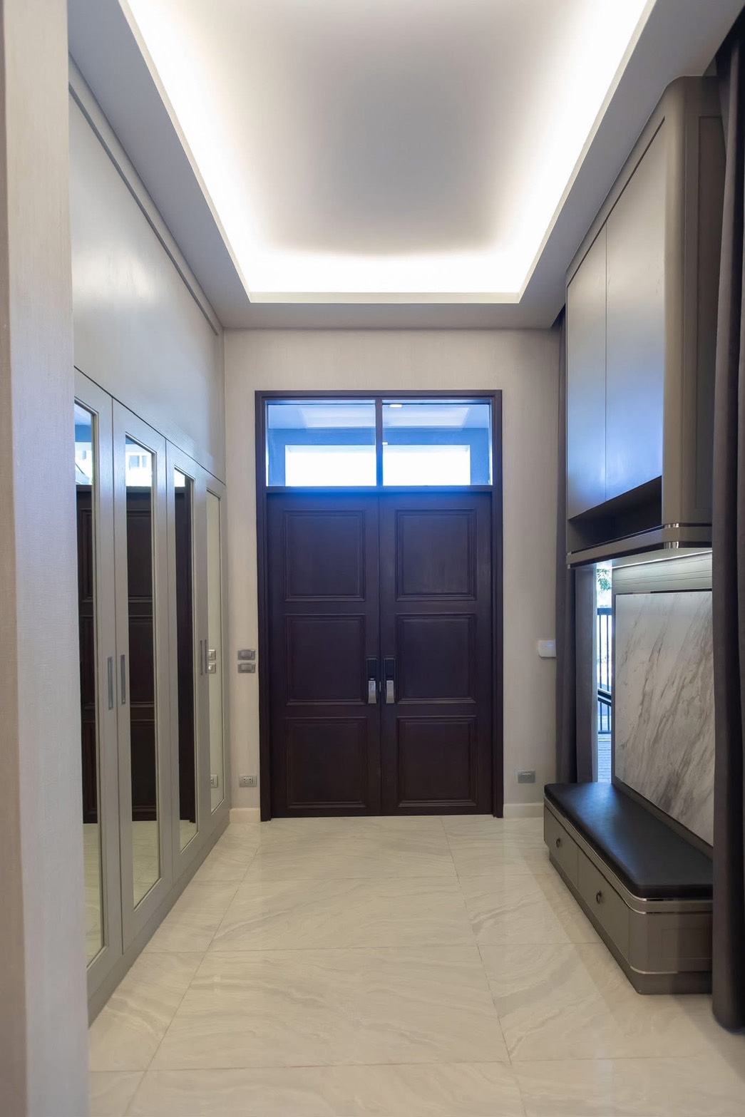 Detached House for rent in Lat Phrao, Bangkok - Entrance foyer with double wooden doors, mirrored wardrobes, and built-in bench storage.