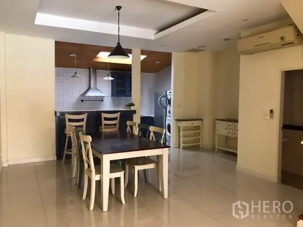 联排别墅 出租在Wang Thonglang, Bangkok - 开放式餐区，六人餐桌与吊灯，连接带天窗的厨房。