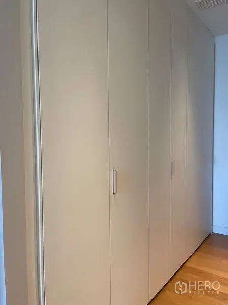 Condominium for rent in Pathum Wan, Bangkok - Built-in floor-to-ceiling wardrobes along a hallway with wood flooring.