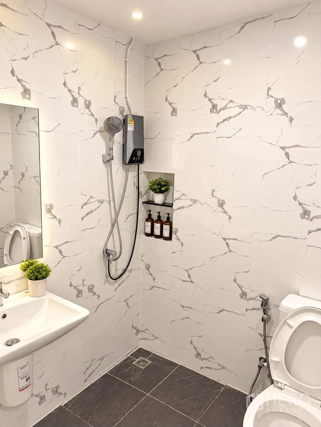 Townhouse for rent in Bang Phli, Samut Prakan - White marble-pattern bathroom with niche shelving, handheld shower, and vanity.