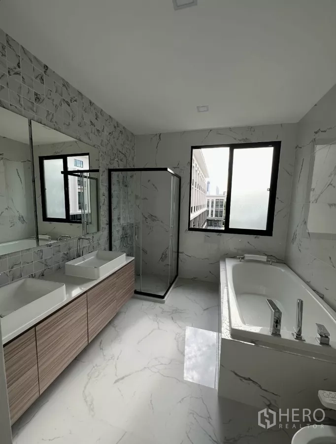 Townhouse for rent in Chatuchak, Bangkok - Modern bathroom with double vanity, glass shower enclosure and bathtub.
