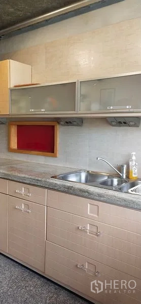 Condominium for sale in Watthana, Bangkok - Close-up of kitchen sink with frosted glass cabinets and tiled backsplash in a Sukhumvit condominium.