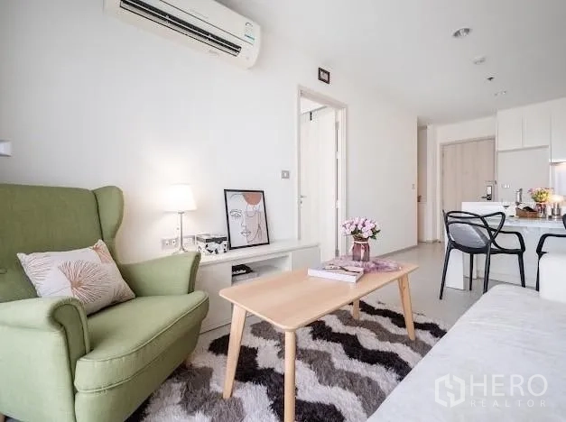 Condominium for sale in Khlong Toei, Bangkok - Close view of seating area with green armchair, coffee table, and patterned rug.