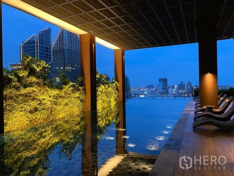 Condominium for rent or sale in Watthana, Bangkok - Rooftop infinity pool with green living wall and panoramic skyline views at dusk.