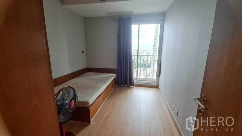 公寓 出租或出售在Watthana, Bangkok - 次卧带单人床、木地板，推拉门通向小阳台。
