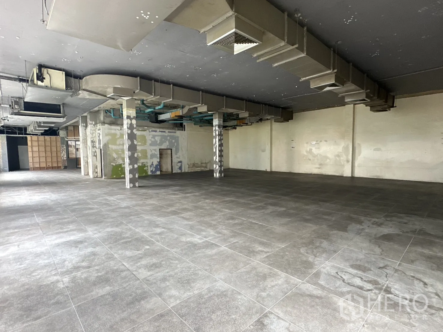 พื้นที่ขายของ for rent in Watthana, Bangkok - มุมมองกว้างของโชว์รูมพื้นกระเบื้อง มีเสาและระบบระบายอากาศ.