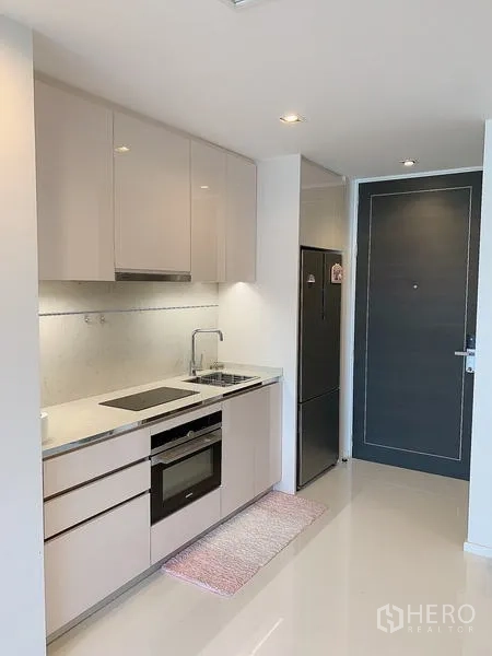 Condominium for sale - Compact kitchenette with built-in hob, oven, and full-height fridge.