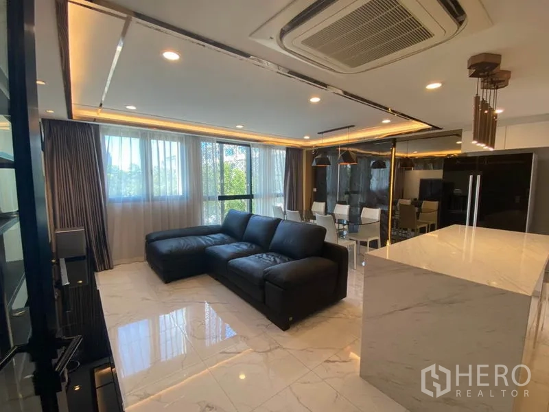 Townhouse for sale in Yan Nawa, Bangkok - Modern lounge with black sofa, marble flooring, dining corner and stone-topped kitchen island.
