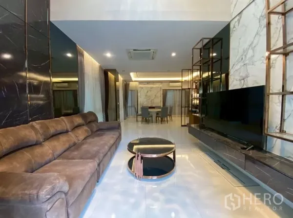 独立式住宅 出租在Prawet, Bangkok - 开放式起居区通向餐厅，亮面地砖与电视墙。