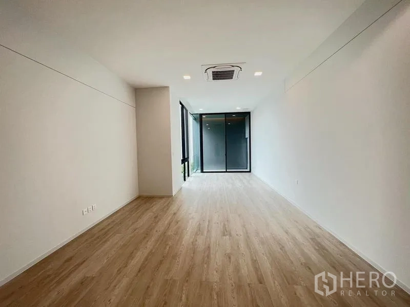 Detached House for rent or sale in Saphan Sung, Bangkok - Bright empty room with light wood flooring and a sliding glass door.