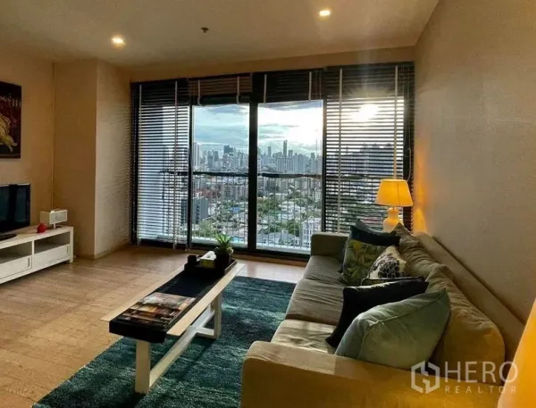 คอนโด ให้เช่าในWatthana, Bangkok - ห้องนั่งเล่นสว่าง โซฟา ตู้วางทีวี และกระจกเต็มบานเปิดรับวิวเมืองแบบพาโนรามา.