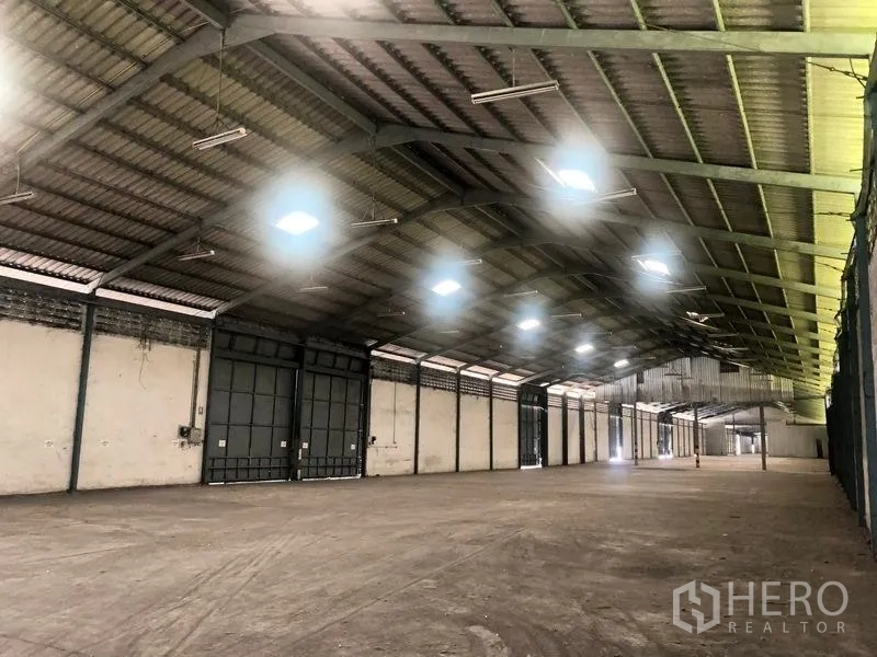 Warehouse for rent in Bang Pa-in, Phra Nakhon Si Ayutthaya - Spacious warehouse interior with high steel truss roof, bright skylights, and large sliding doors.
