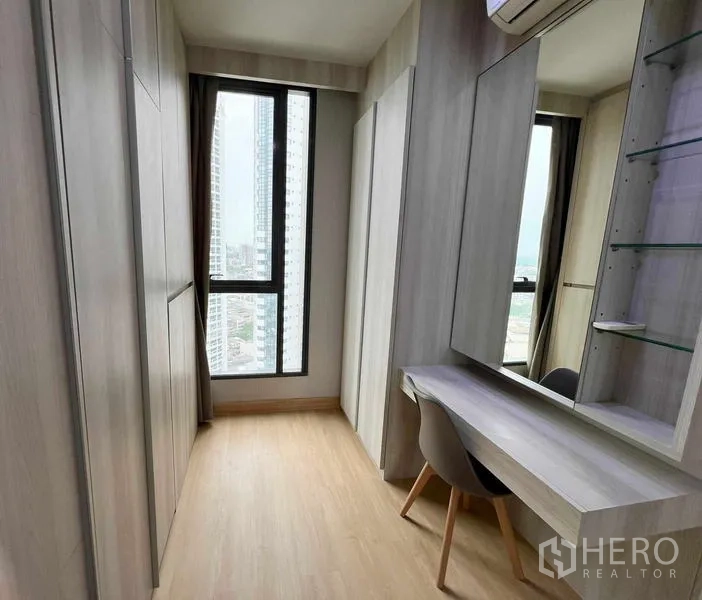 Condominium for rent or sale - Narrow dressing corridor with vanity, glass shelving, and tall window.