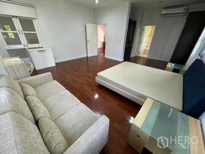 Detached House for rent in Prawet, Bangkok - Large master bedroom with sofa seating, wooden floors and access to an ensuite.