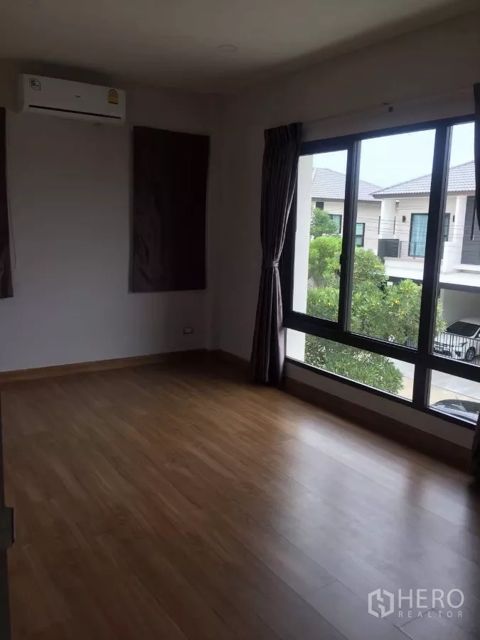 独立式住宅 出租在Samut Prakan - 楼上宽敞卧室，大转角窗、木地板与空调。