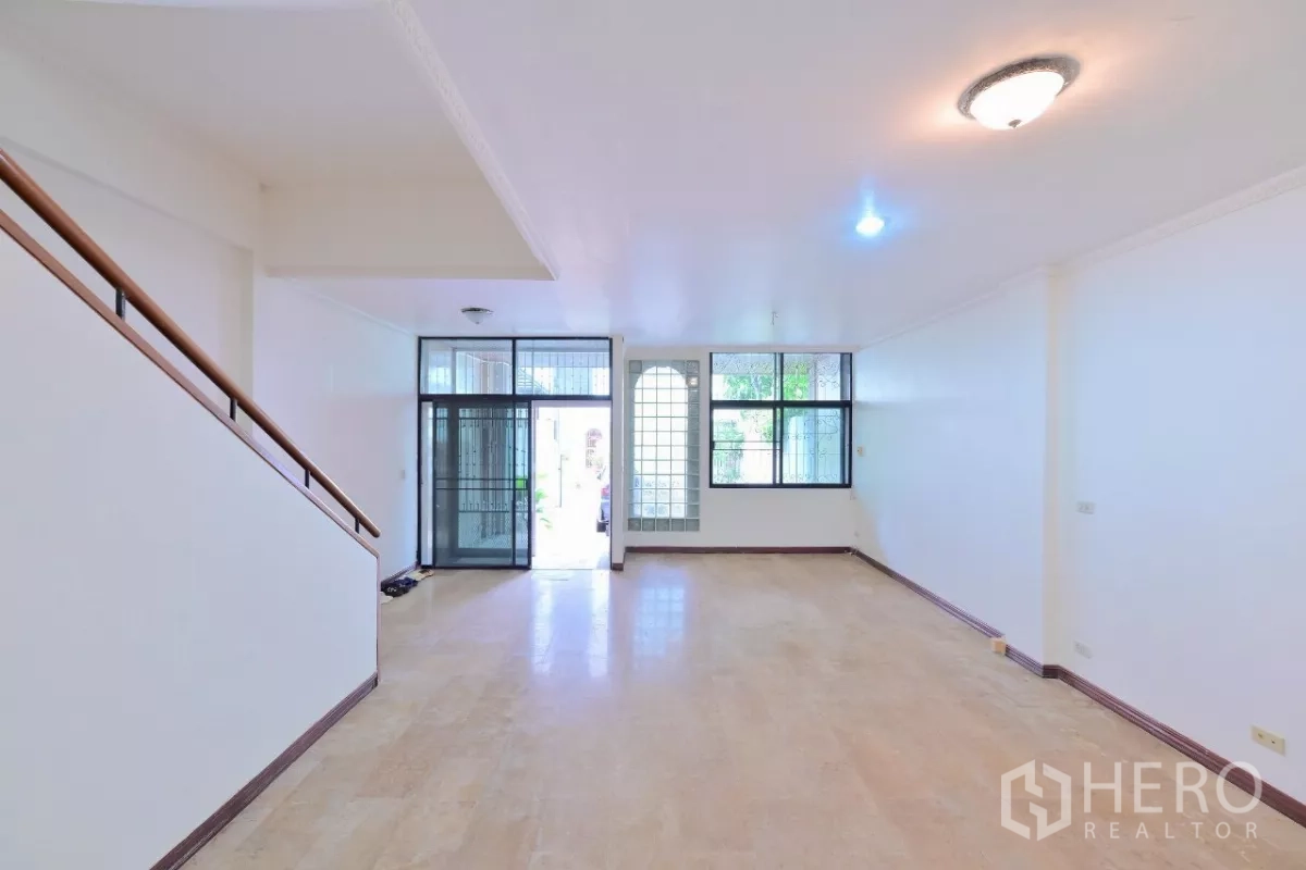 联排别墅 出售在Watthana, Bangkok - 从楼梯望向前厅，可见玻璃砖窗与推拉入户门。