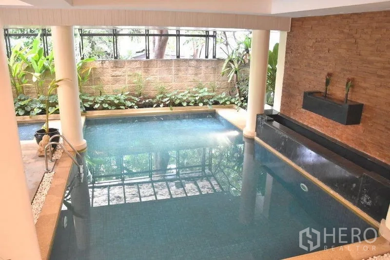 Apartment for rent in Sathon, Bangkok - Indoor swimming pool with water feature and garden edging.