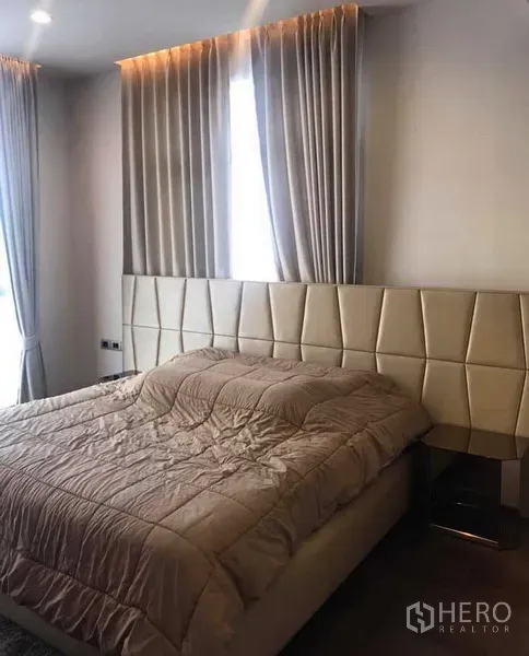 Condominium for rent or sale in Watthana, Bangkok - Primary bedroom with padded headboard, soft lighting and tall curtains.
