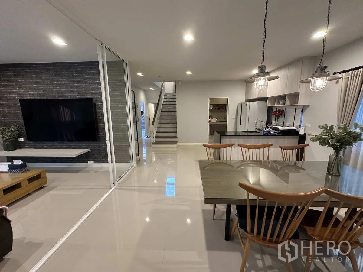 Detached House for rent or sale in Lam Luk Ka, Pathum Thani - Dining zone beside kitchen facing TV feature wall and staircase.