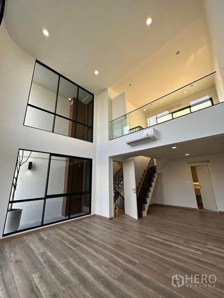 Townhouse for rent in Yan Nawa, Bangkok - Open-plan living area with mezzanine, staircase and full-height windows.